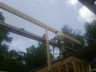 Carpenter setting a ridge beam over a new addition frame — Ice Dam Removal by Roofing Brothers in Baldwinville