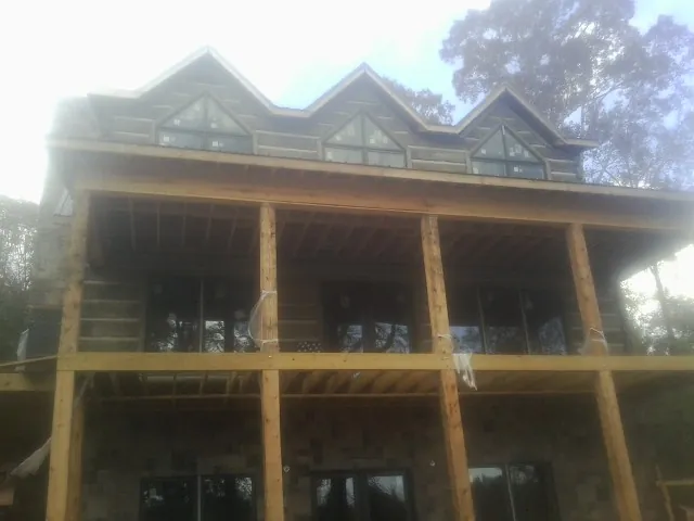 Dormers and porch framing on a large log home under construction — Roof Coating work by our crew in Baldwinville
