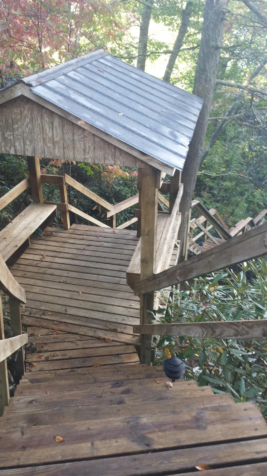 Metal roofed shelter over wooden steps on a wooded walkway — Skylight Repair & Installation work by our crew in Baldwinville