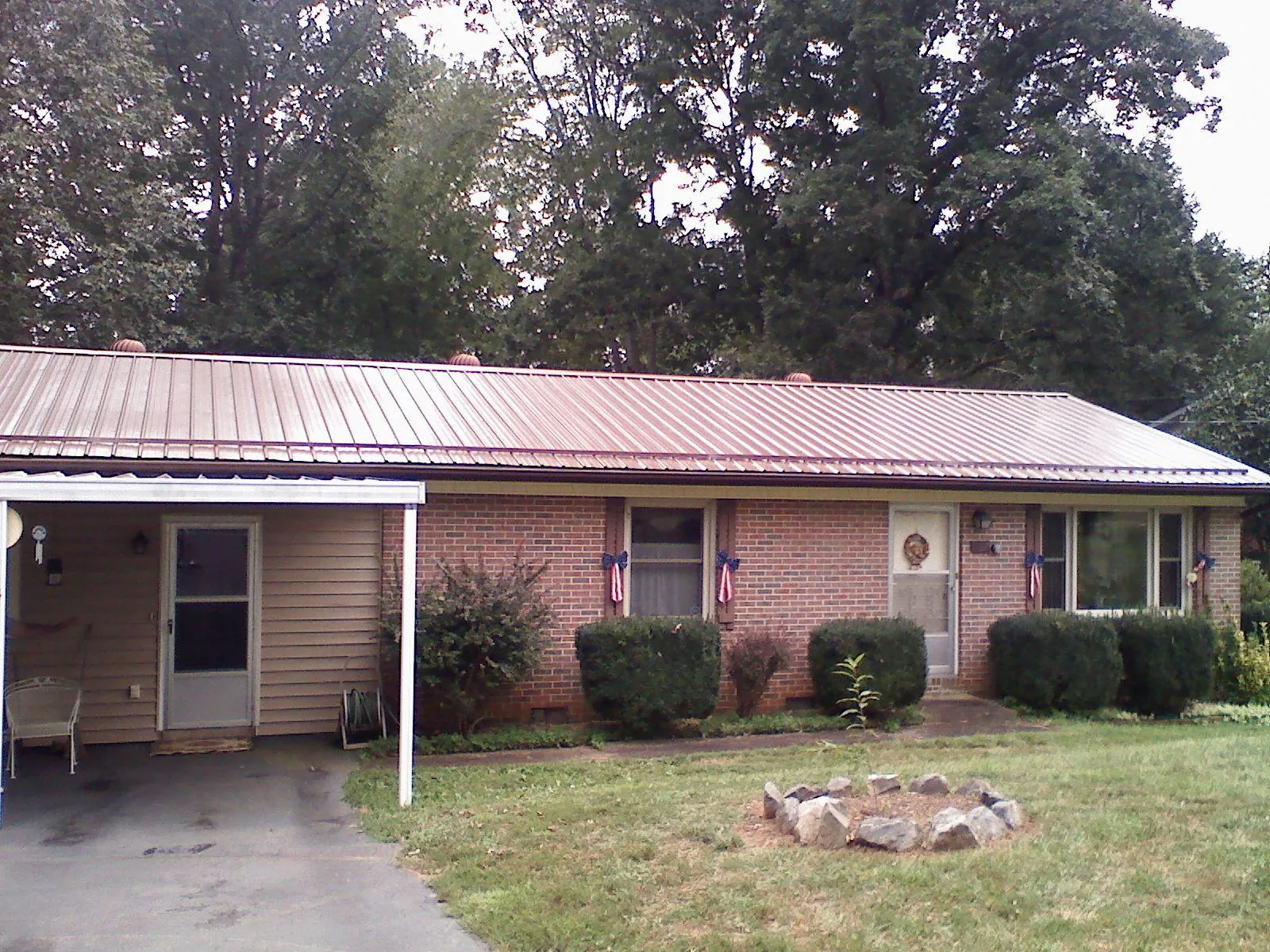 Bronze metal roof and carport on a brick ranch home — Roof Repair work by our crew in Baldwinville